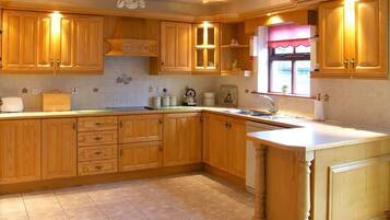 A kitchen with wooden cabinets, a countertop, a sink, and a window with a curtain.