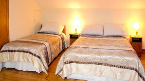 Deux lits doubles avec des têtes de lit assorties, des tables de chevet avec des lampes et un plancher en bois.
