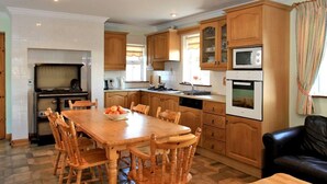 A spacious kitchen with wooden cabinets, a dining table, and chairs. - 4 Bed in Caherdaniel (oc-ii04851) (Caherdaniel)