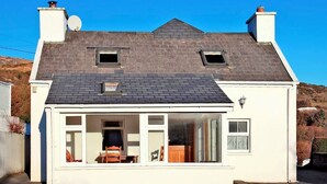 A two-story house with a sloped roof, a satellite dish, and a large windowed porch area. - 4 Bed in Caherdaniel (oc-ii04851) (Caherdaniel)