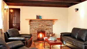 A cozy living room with a fireplace, leather sofas, and a wooden coffee table. - 4 Bed in Caherdaniel (oc-ii04851) (Caherdaniel)