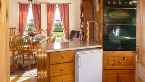 A kitchen with wooden cabinets, a refrigerator, and an oven. - 3 Bed in Achill Island (oc-ii06848) (Doogort)