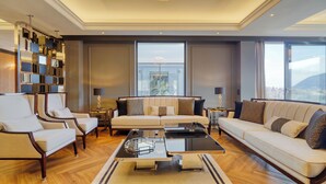 Un salon spacieux comprenant un ensemble de canapés, des fauteuils, une table basse et un téléviseur fixé au mur.