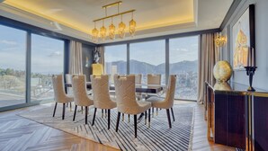 Un espace repas offrant une vue sur les montagnes, agrémenté d’un lustre et d’une statue.