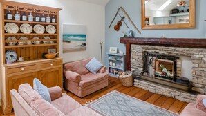 Ein gemütliches Wohnzimmer mit Kamin, Bücherregal und einem Strandbild.