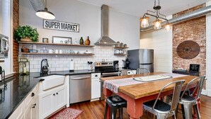 Une cuisine moderne avec des meubles blancs, un réfrigérateur en acier inoxydable et une enseigne indiquant « SUPER MARCHÉ ».