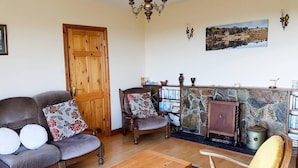 Un salon comprenant un canapé, un fauteuil, une table basse en bois et un tapis.