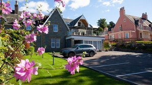 Un quartier résidentiel avec des maisons en pierre, une voiture garée et des fleurs en pleine floraison.