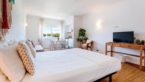 Une chambre d’hôtel comprenant un lit, un bureau avec une télévision, un coin repas et une fenêtre donnant sur un paysage agréable.