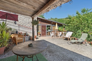 An outdoor patio with a wooden table, wicker chairs, and potted plants. - Holiday Home 'La Casa Di Pietra - Maissana' with Mountain View, Private Terrace and Private Garden (Varese Ligure)