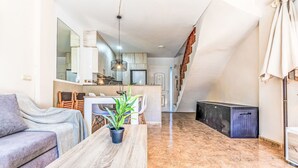 Una sala de estar moderna con un sofá, una mesita de centro y un comedor con sillas y una planta.