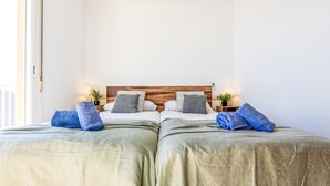Habitación doble con dos camas, cabecero de madera, lámparas de noche y vistas al exterior.