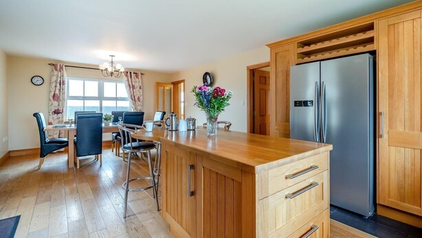 Een moderne keuken met houten kastjes, een roestvrijstalen koelkast en een eethoek met een tafel en stoelen.