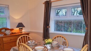 A dining table set for four with a polka dot tablecloth, wooden chairs, and a vase with yellow flowers. - 2 Bed in Castlemaine (oc-ii08066) (Aughills)