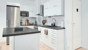 Eine moderne Küche mit weißen Schränken, einem Edelstahlkühlschrank, einer Mikrowelle und einer Kaffeemaschine.
