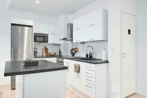 Een moderne keuken met witte kasten, een roestvrijstalen koelkast, een magnetron en een koffieapparaat.