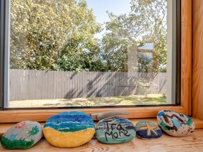 A window with a view of a backyard, a wooden fence, and a row of painted rocks on a windowsill. - 3 Bed in Tramore (oc-ii11304) (Tramore)