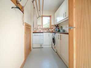 A compact kitchen with a washing machine, a dishwasher, and wooden cabinets. - 3 Bed in Tramore (oc-ii11304) (Tramore)