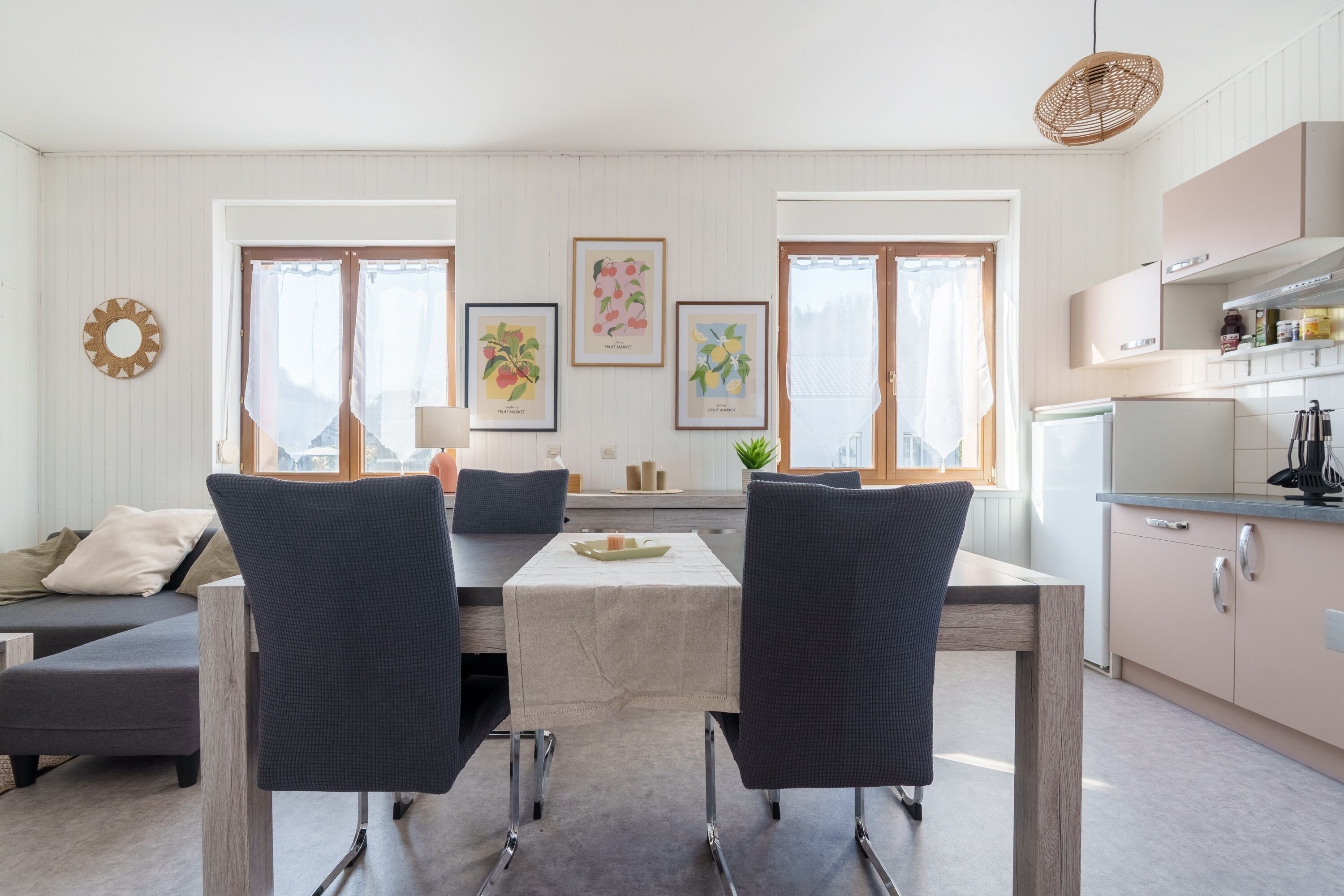 A modern kitchen with white cabinetry, a dining area with a table and chairs, and artwork on the walls.
