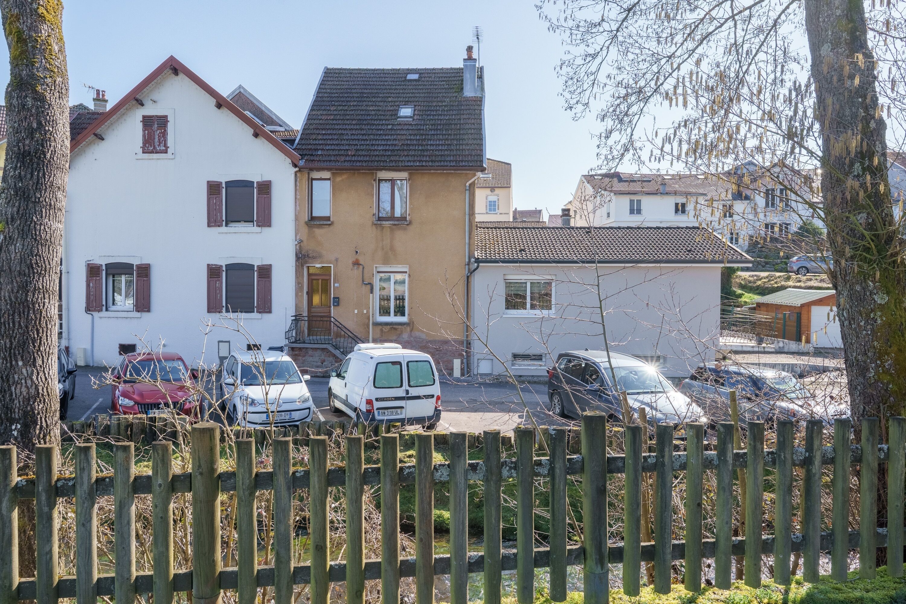 A residential area with houses, parked cars, and a wooden fence.