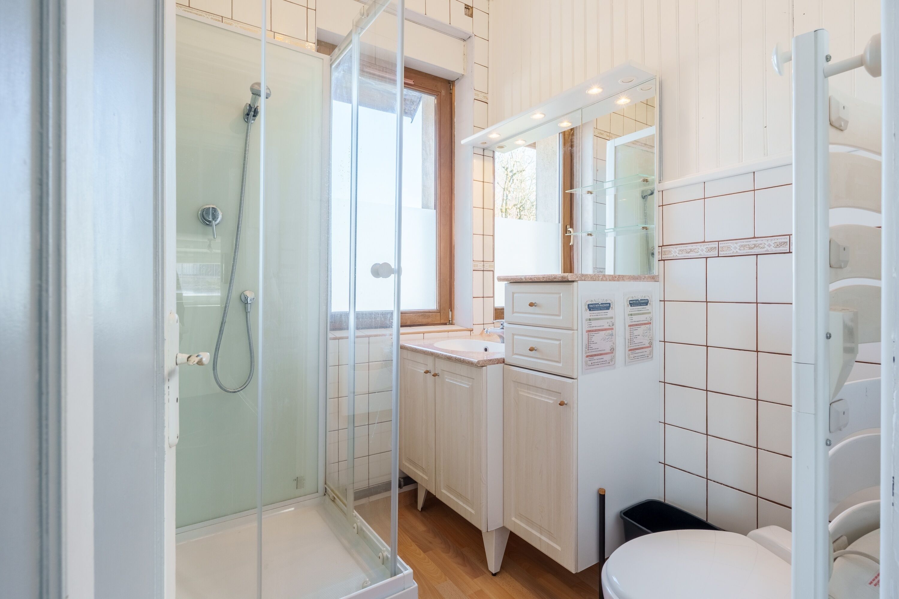 Ein Badezimmer mit Duschkabine, Waschbecken, Toilette und Spiegel.