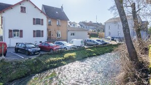 Eine Wohnstraße mit parkenden Autos, Häusern und einem kleinen Bach.