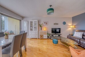 Ein modernes Wohnzimmer mit Essbereich, einer Couch, einem Fernseher und einer Lampe.