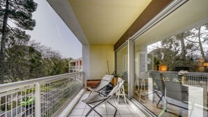 A balcony with two lounge chairs, a glass door, and a view of trees and a building. - Le Halo - Avec Balcon et Parking Privé (Le Bouscat)