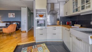A modern kitchen with white cabinets, a stainless steel range hood, and a black tiled backsplash. - Le Halo - Avec Balcon et Parking Privé (Le Bouscat)