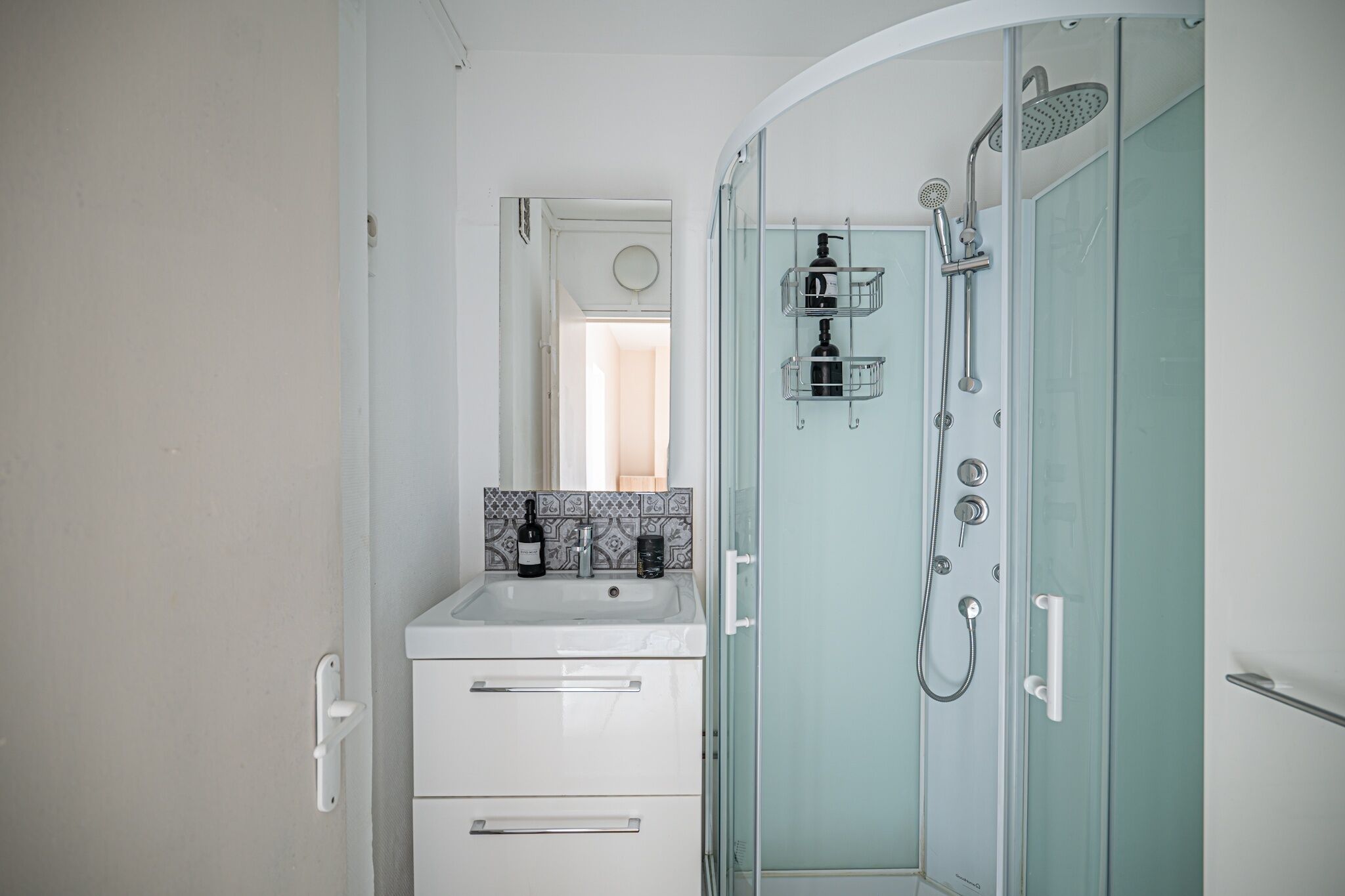 A bathroom with a white sink, a mirror, a towel rack, and a glass-enclosed shower area.