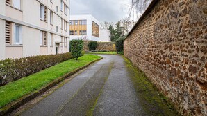 Una calle estrecha bordeada por edificios modernos con muros de piedra y un área con césped.