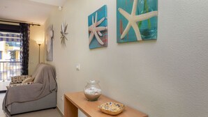 Un salón con sofá, una consola decorada con adornos y dos cuadros de estrellas de mar en la pared.