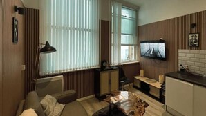 A compact living space with a sofa, a coffee table, a television, and a kitchenette. - The Halifax Suites near Albert Dock (Liverpool)