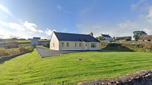 A single-story house with a sloped roof, a paved driveway, and a well-maintained lawn. - 3 Bed in Dingle (oc-ii00613) (Feohanagh)
