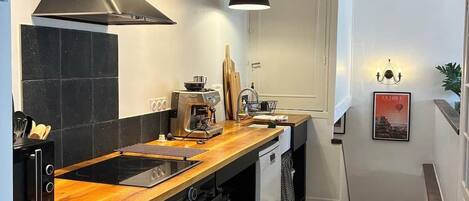 A modern kitchen with a black and white checkered floor, a wooden countertop, and a black range hood.