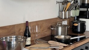 Cucina con elettrodomestici in acciaio inossidabile, una bottiglia di vino, bicchieri e diversi utensili.