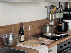 A kitchen with stainless steel appliances, a wine bottle, glasses, and various utensils. - Casa Wechi: 3-Bedroom Central Pool Home For Families in a Secured Neighbourhood (Willemstad)