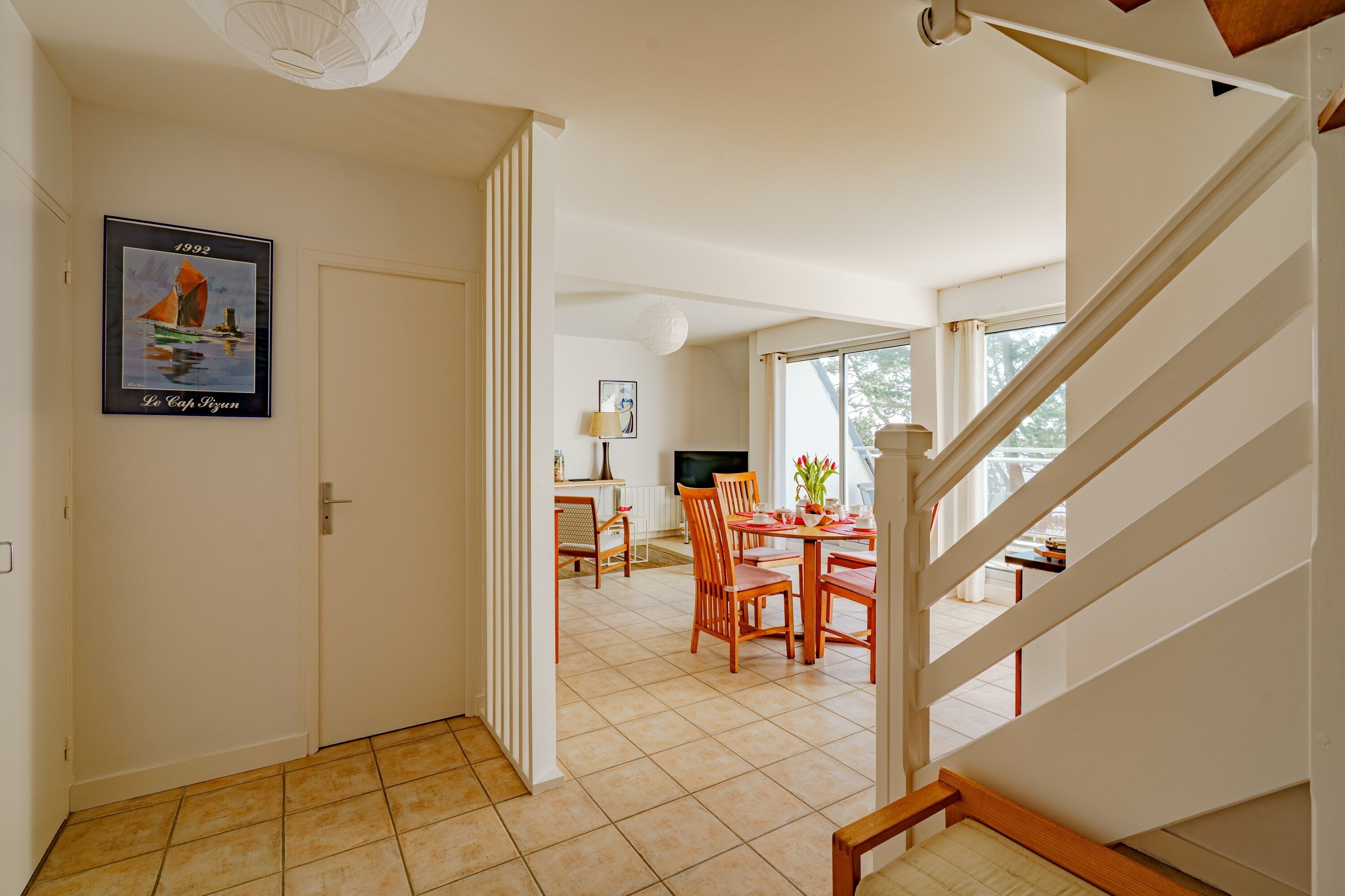 Un coin repas avec une table et des chaises, un téléviseur et un tableau encadré au mur.