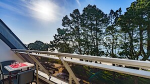 Un balcone con tavolo e sedie, con vista su una foresta e un corpo d'acqua.