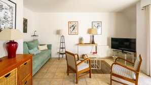 Un soggiorno con divano, poltrone, televisore e opere d'arte alle pareti.