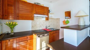 Una cucina con mobili in legno, lavastoviglie integrata, un piano di lavoro rosso, un lavello e uno specchio.