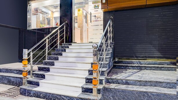 Un escalier avec des marches en marbre et des rampes de garde-corps en métal menant à l’entrée d’un bâtiment.