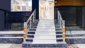 Un escalier avec des marches en marbre et des rampes en métal menant à un espace intérieur.