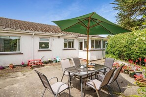A patio with a table, chairs, and a green umbrella.
