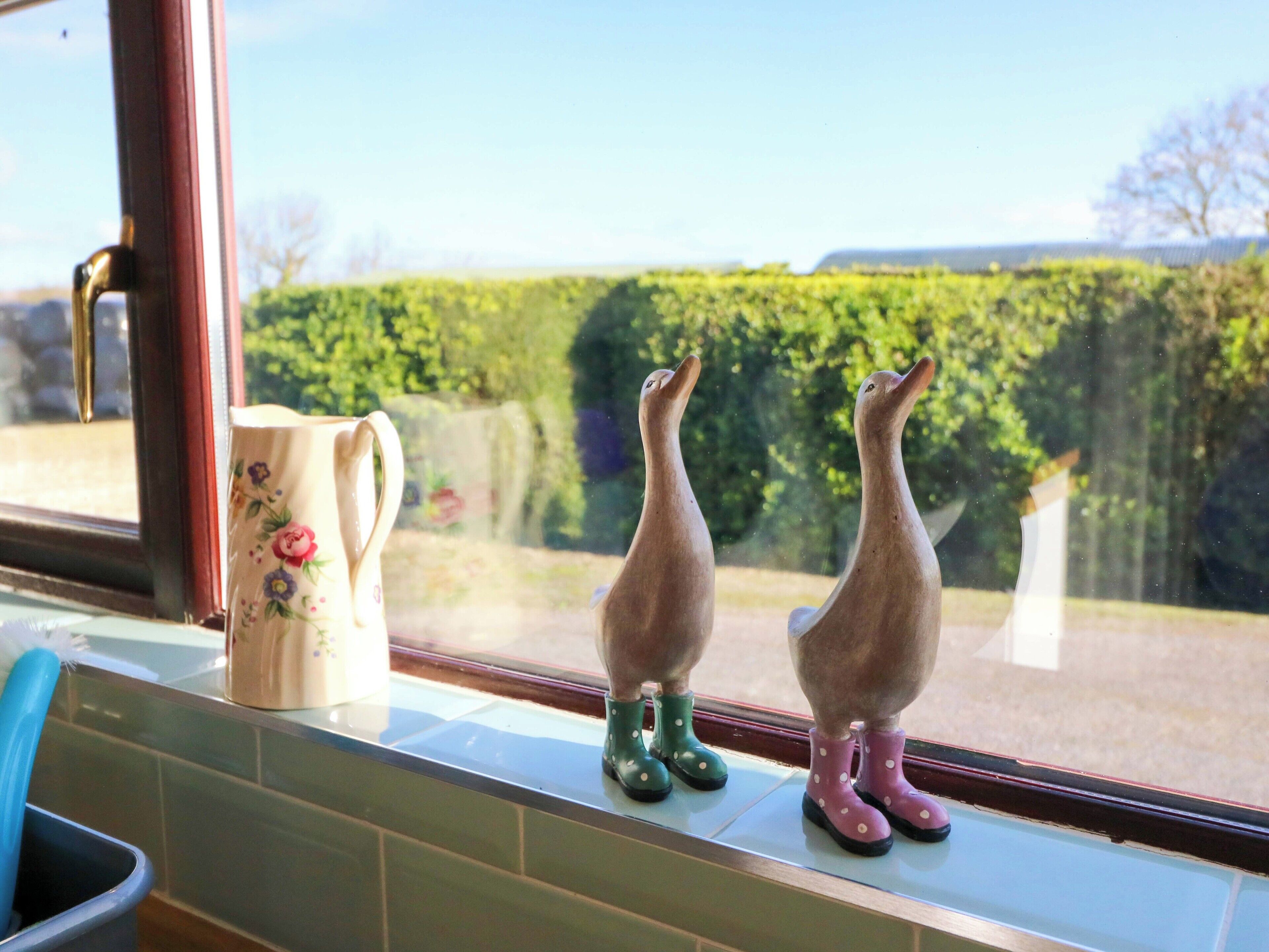 Two ceramic figurines on a window sill, a floral mug, and a blue chair.