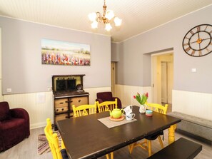 A dining area with a table, chairs, a chandelier, a clock, and a painting on the wall. - Thadg and Hannahs (Dromin)