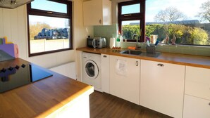 Eine Küche mit Waschmaschine, Toaster und einem Fenster mit Blick auf Bäume.
