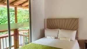 A room with a bed, a wooden ceiling, and a view through a glass door. - Hotel y termales Las Heliconias (Zetaquira)