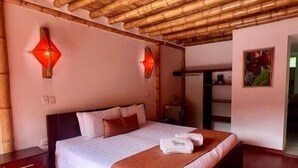 A room with a bed, wooden flooring, a bamboo ceiling, and wall-mounted lights. - Hotel y termales Las Heliconias (Zetaquira)