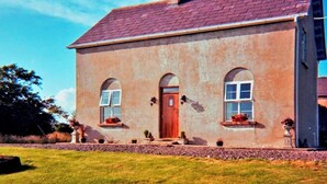 Une maison à deux étages avec une façade en briques, une porte en bois et des fenêtres en arc de cercle.